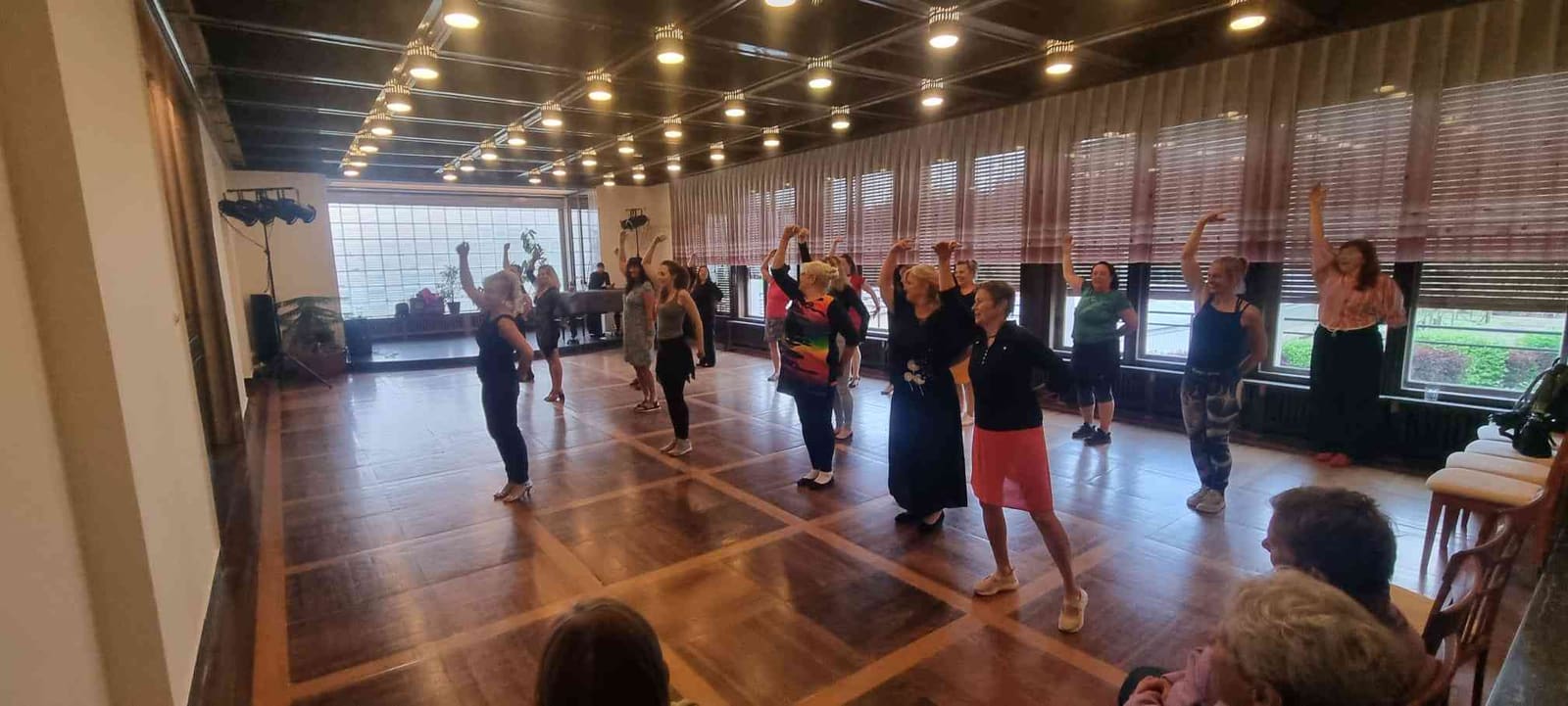 Plný taneční sál během večera Lady Dance — tanečnice s rukama nad hlavou.